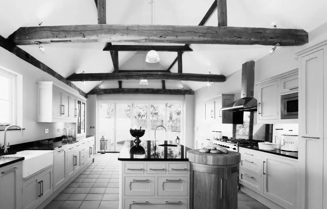Cuisine de ferme en noir et blanc, poutres apparentes et îlot central