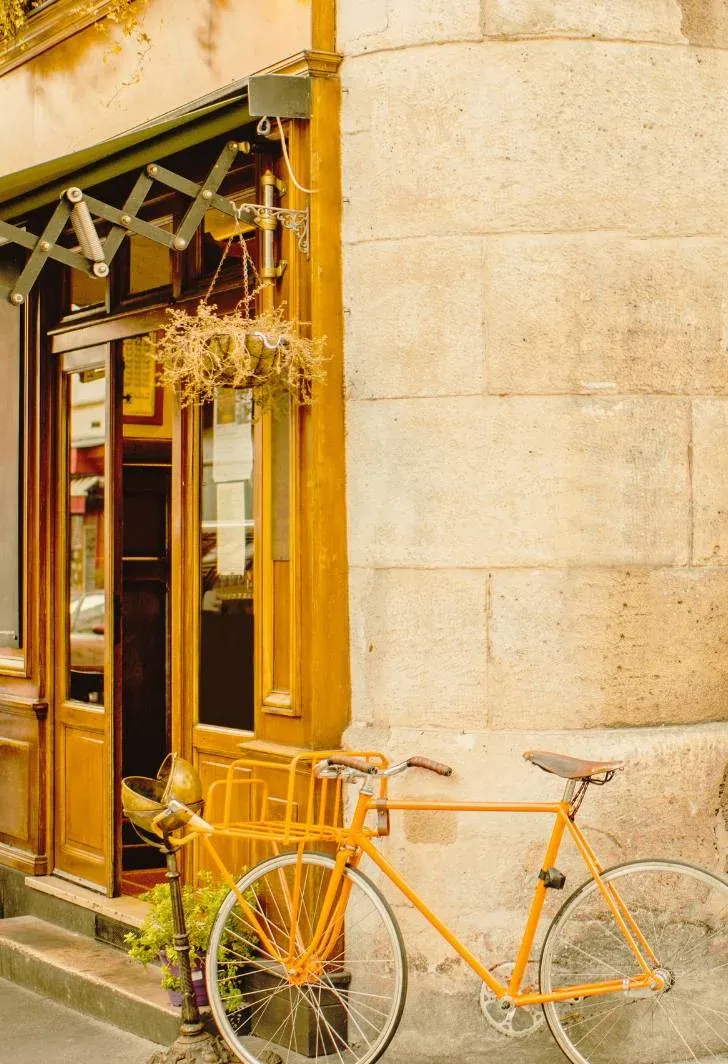 Façade ancienne en pierre blonde, porte vitrée en bois et vélo jaune rétro